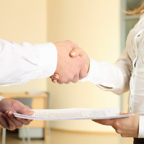 Man and woman shaking hands in office and giving papers